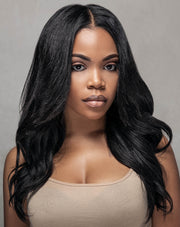 A woman with long, straight black hair wearing a beige top and clip-in hair extensions for natural silk press.